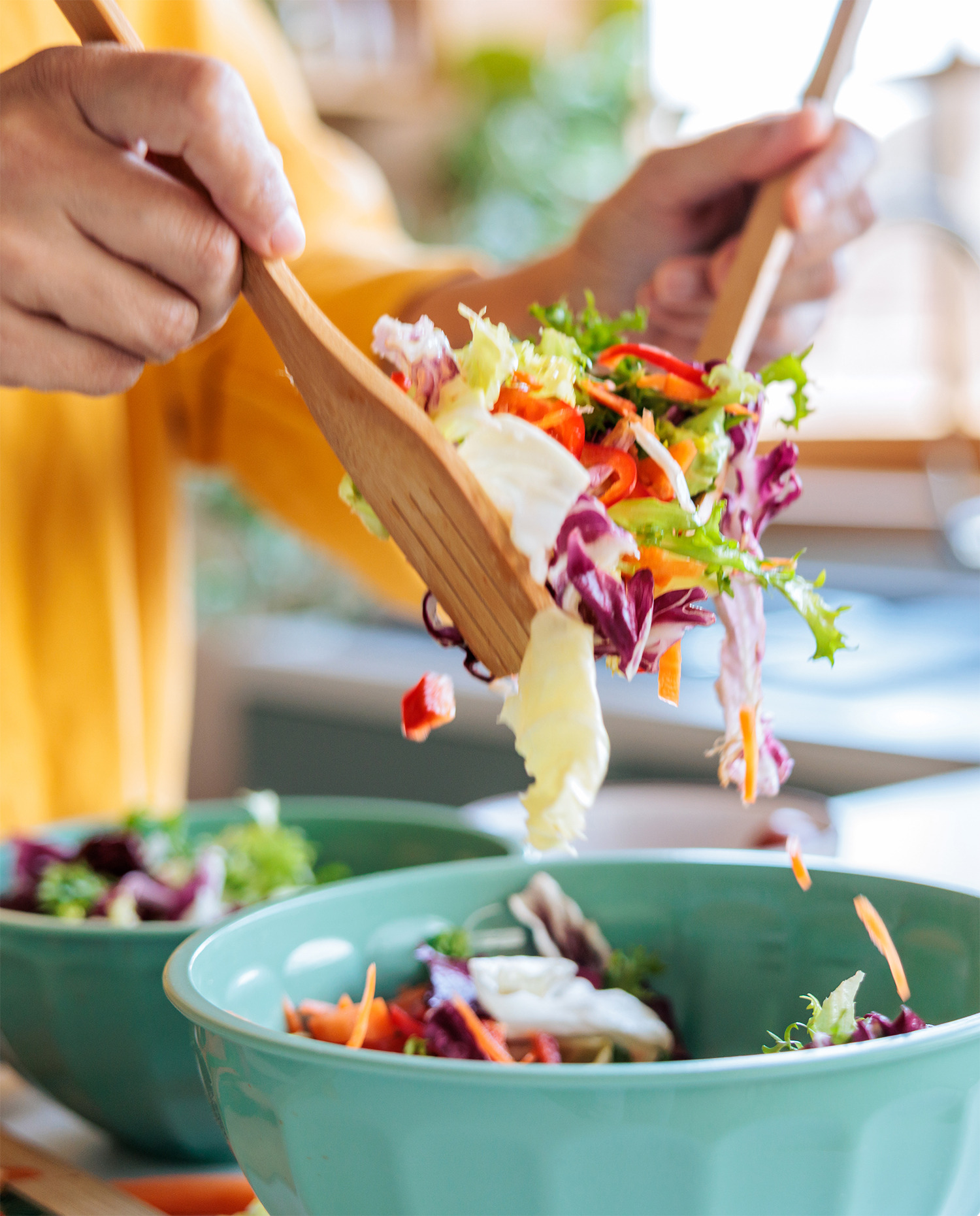 Tossing a colorful fresh salad into a serving bowl